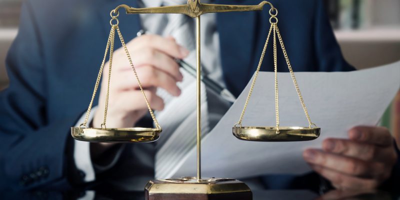 Weight scale of justice, lawyer in background Weight scale of justice, lawyer in background. lawyer law justice judge scales courtroom legal scale concept